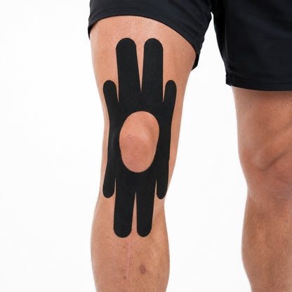 Svart förklippt kinesiologitejp med 4-vägsdesign applicerad runt knät.
