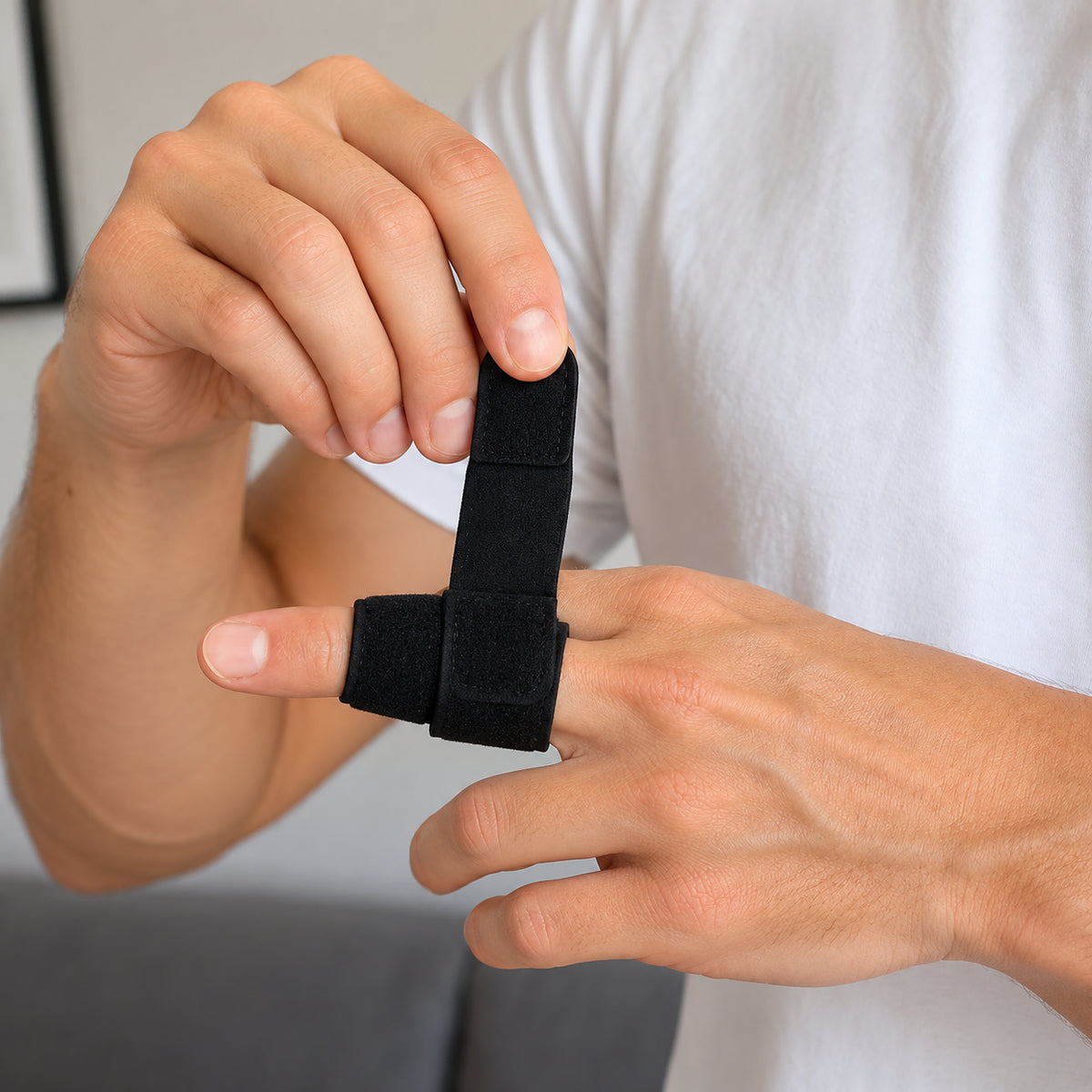 Person justerar ett svart fingerstöd med lätt kompression och anpassningsbar passform runt fingret.