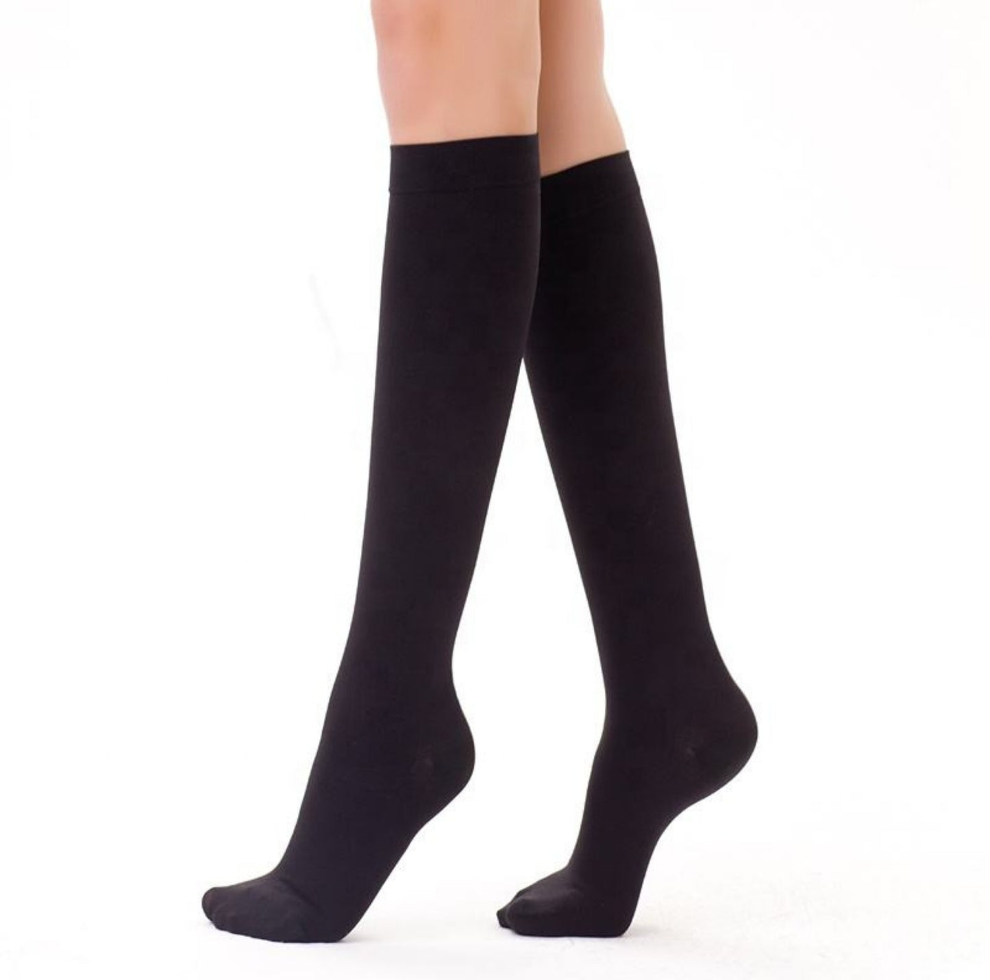 Svarta knähöga strumpor burna på ben mot vit bakgrund.