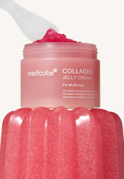 Medicube Collagen Jelly Cream med rosa gel på spatel, placerad ovanpå en rosa burk mot ljus bakgrund.
