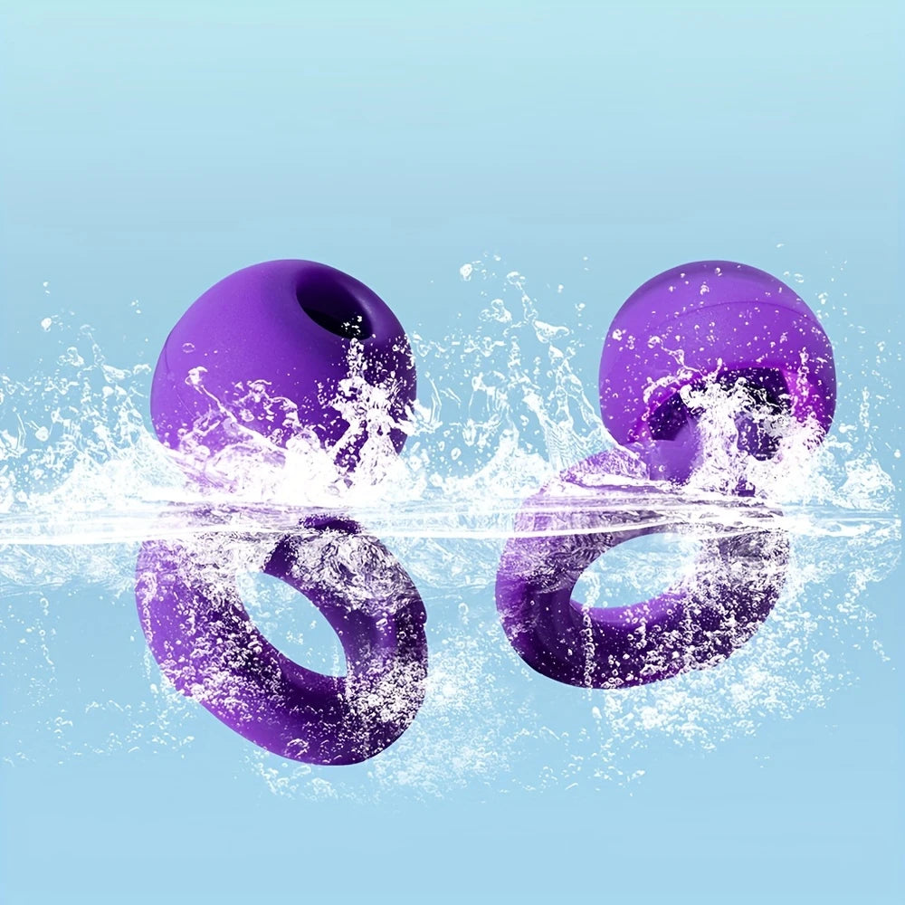 Två lila silikonöronproppar som nedsänks i vatten med stänk, mot ljusblå bakgrund.